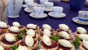 Scones, jam, cream and teacups on table